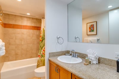 A wide vanity mirror reflects soft recessed lighting, opening the space with a clean and airy sense of coastal calm