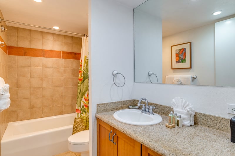 A wide vanity mirror reflects soft recessed lighting, opening the space with a clean and airy sense of coastal calm