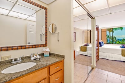 Soft lighting and a view into the suite beyond connect bedroom and bath, inviting a seamless flow of light and tranquility