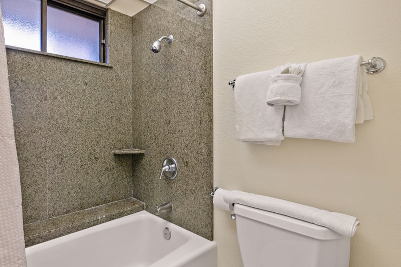 The tub-shower combo features sleek, speckled wall panels, a built-in ledge, and a polished chrome fixture for easy luxury KS-535