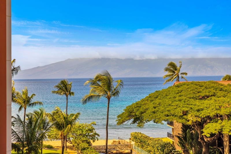 Just steps from the sand, this elevated view showcases Maui’s lush coastline and the calm, blue waters of the Pacific.