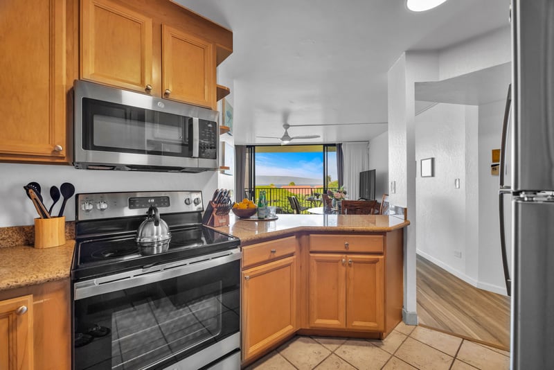 Fully equipped kitchen with granite countertops and stainless steel appliances, opening to ocean views and the airy main living space.
