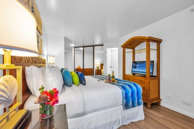 King bedroom with mirrored closet, flat-screen TV, and tropical hardwood furnishings for a comfortable and inviting island escape.