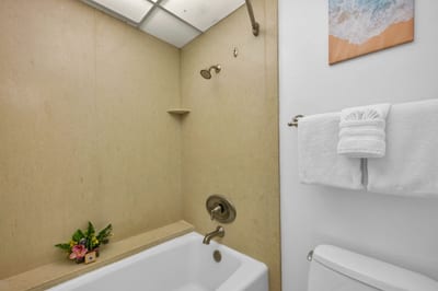 Tub-shower combo with neutral tile surround and soft towels, ideal for a relaxing soak or quick rinse after the beach.