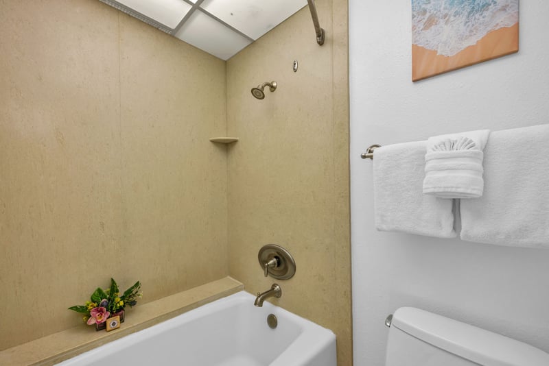 Tub-shower combo with neutral tile surround and soft towels, ideal for a relaxing soak or quick rinse after the beach.
