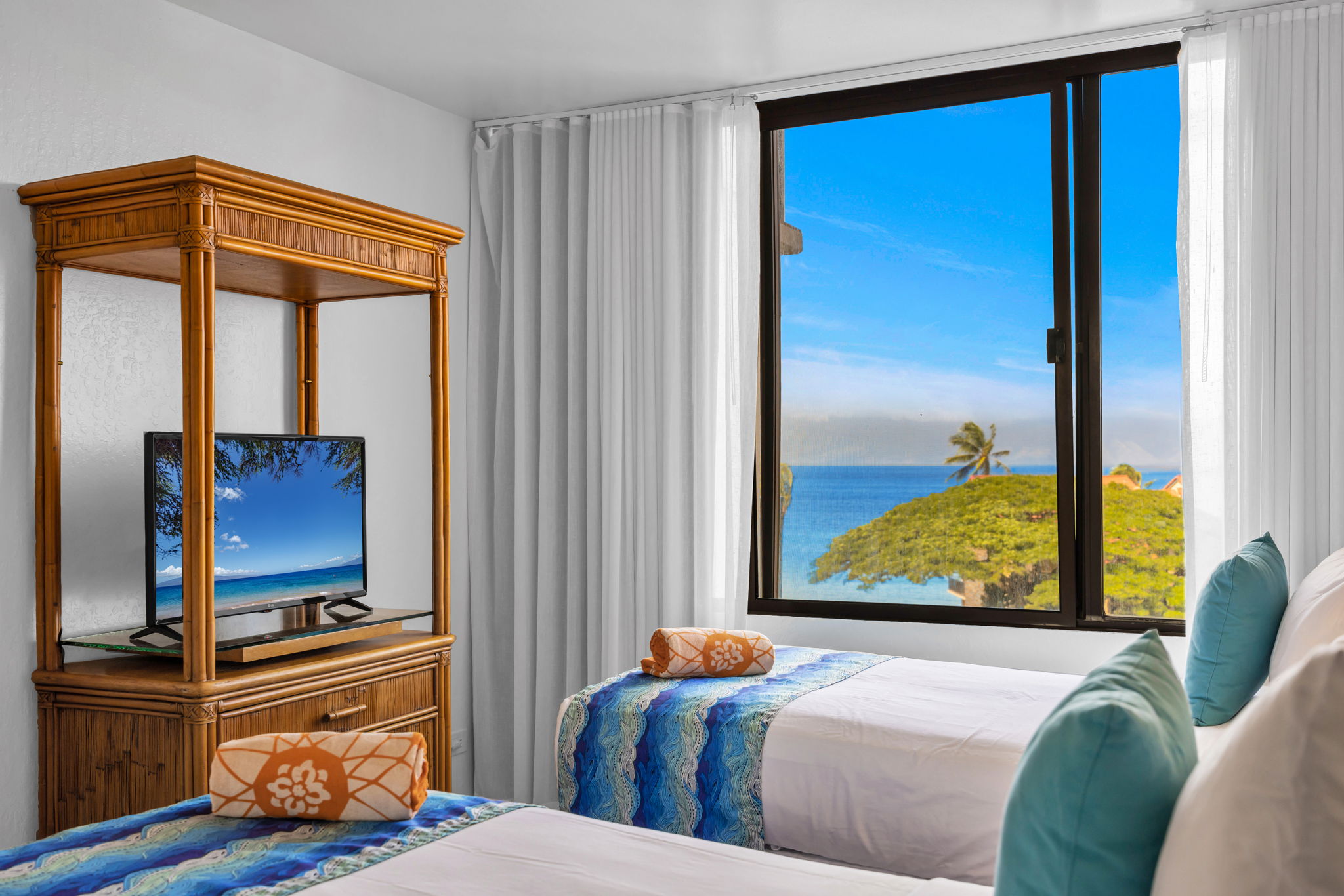 Guest bedroom with two Twin beds, ocean views, and a flat screen TV, ideal for families or friends sharing a comfortable island stay. KS-616