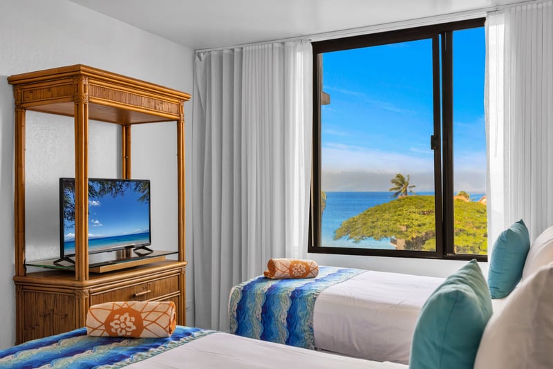 Guest bedroom with two Twin beds, ocean views, and a flat screen TV, ideal for families or friends sharing a comfortable island stay.