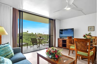 Bright living area with tropical wood furnishings, a large Smart TV, and seamless flow to the lanai for indoor-outdoor lounging.