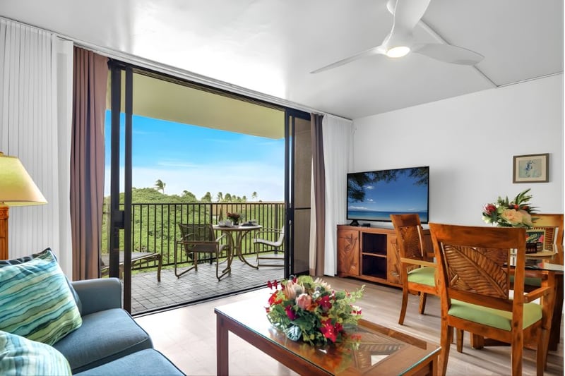 Bright living area with tropical wood furnishings, a large Smart TV, and seamless flow to the lanai for indoor-outdoor lounging.