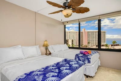A sunlit space with bold bedding, beachy ceiling fans, lanai peeks, and a wardrobe ready for your island looks