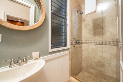 This charming guest bath features a walk-in stone shower, pedestal sink, and soothing coastal tone