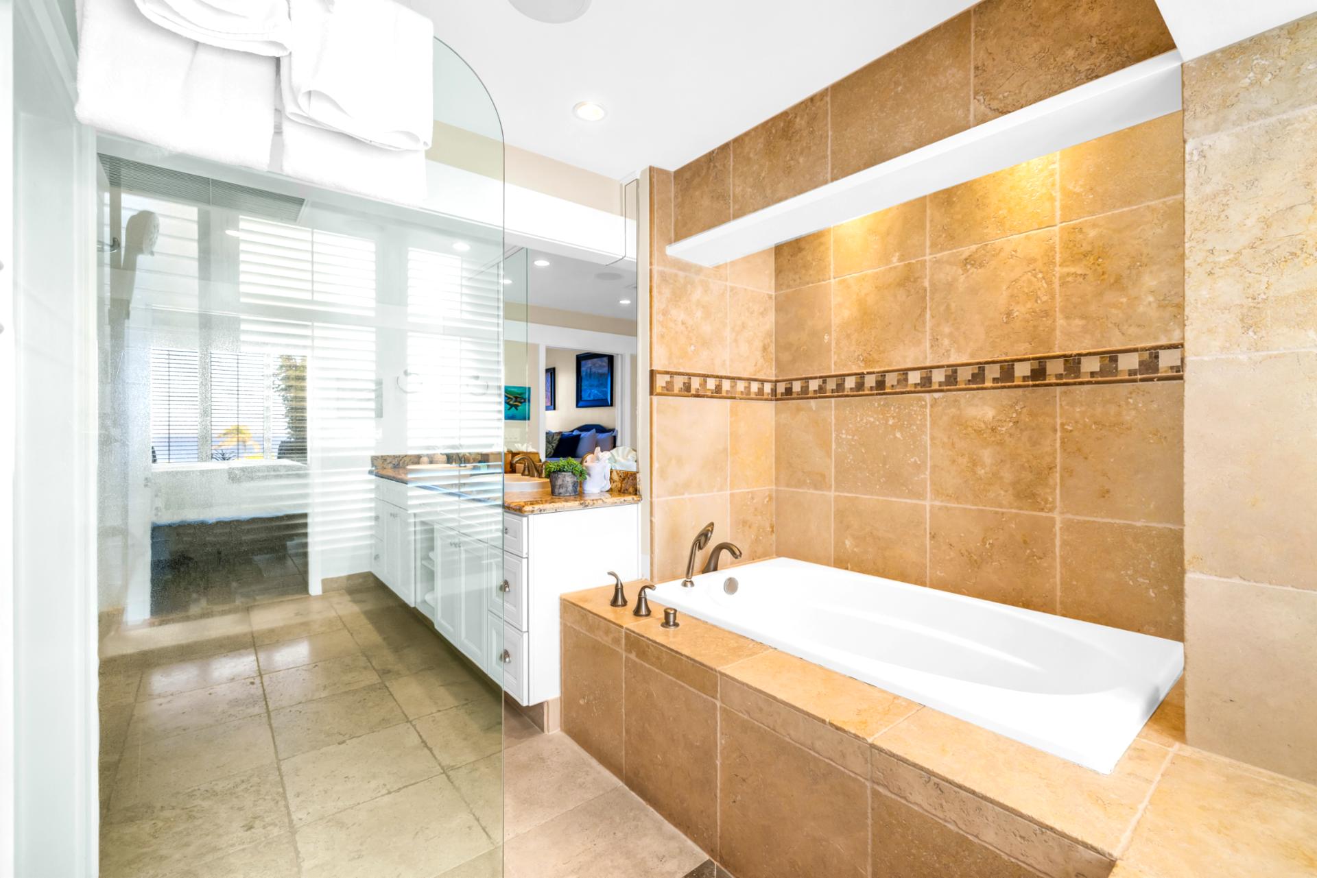 The guest bathroom features an updated glass walk in shower and separate soaking tub for ultimate relaxation