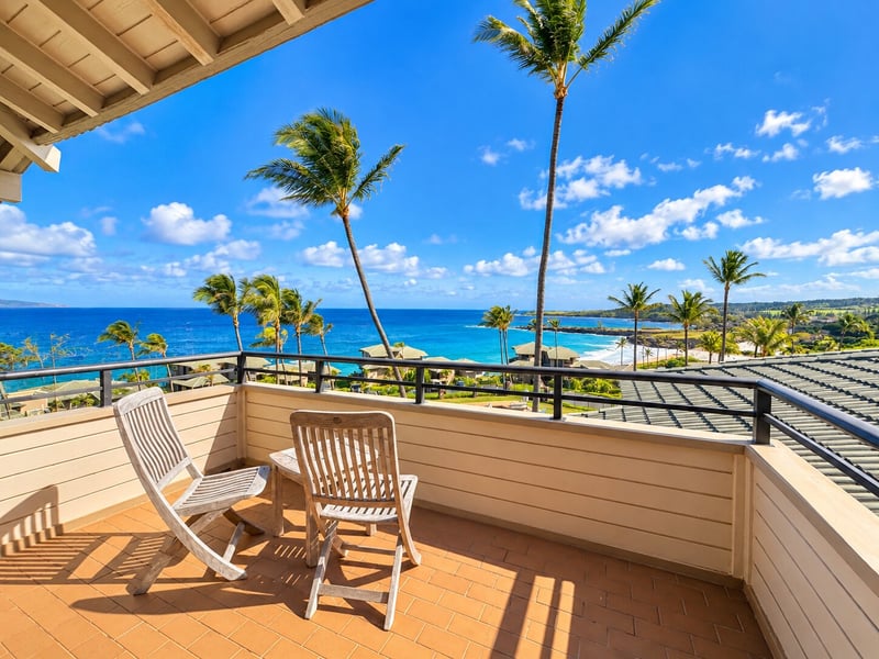 Two wooden chairs on the balcony face the Pacific, swaying palms, and the coastline, creating an easy spot for morning coffee. KBV-15B3
