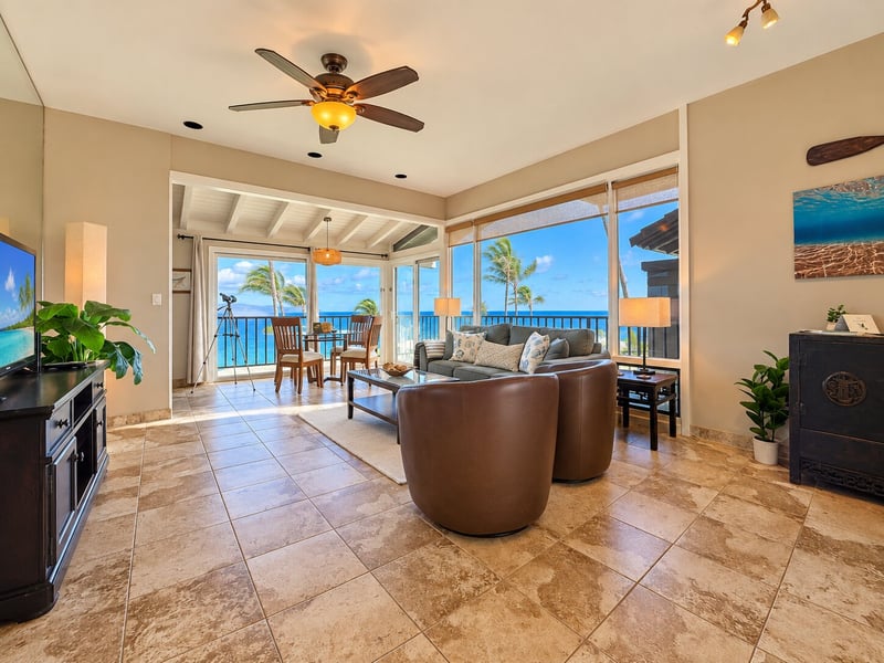 Open living space flows toward wide windows and the dining area beyond, with ocean views, swivel chairs, and a sofa grouped around the coffee table. KBV-15B3