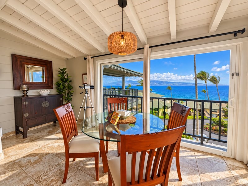 Your dining area sits beside a sliding door to the balcony, with ocean and coastline views beyond the glass table. KBV-15B3