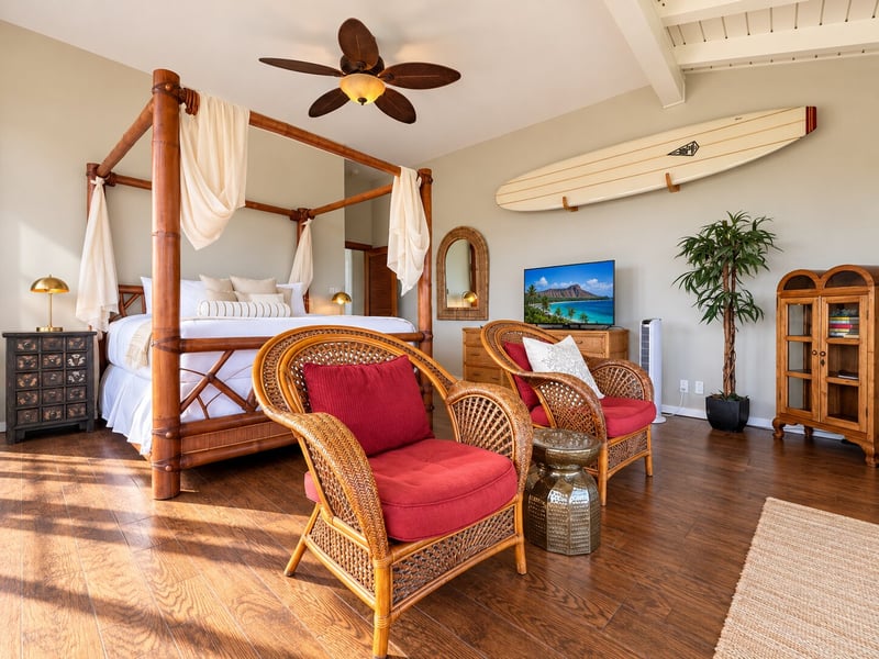 Your bedroom pairs a four-poster king bed with wicker armchairs, a television, a dresser, and a display cabinet. KBV-15B3