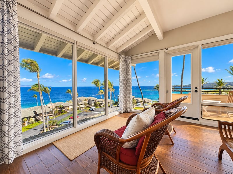 Cushioned wicker chairs by the windows make a quiet spot to watch the ocean, with the balcony door steps away. KBV-15B3