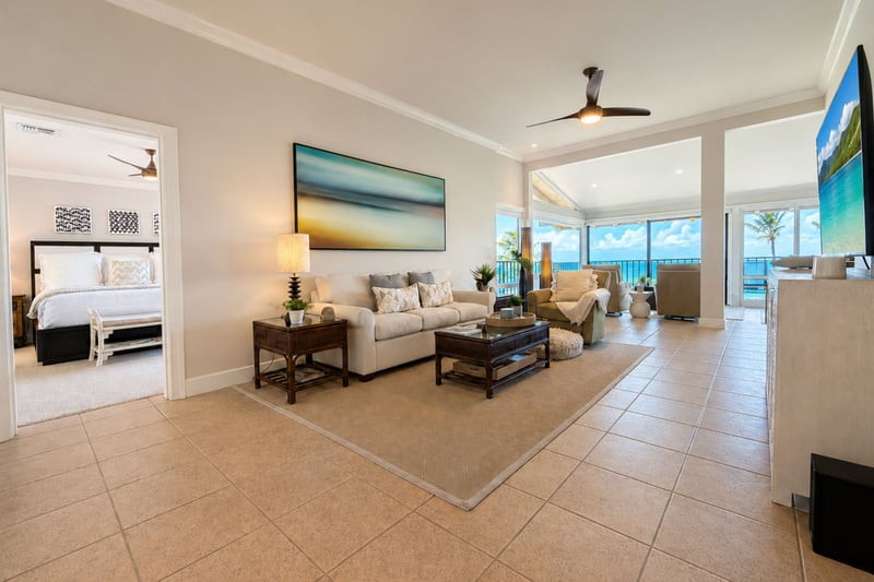 Your living room opens onto the lanai through sliding glass doors, with a comfortable sofa and armchair arranged for ocean-view conversation.