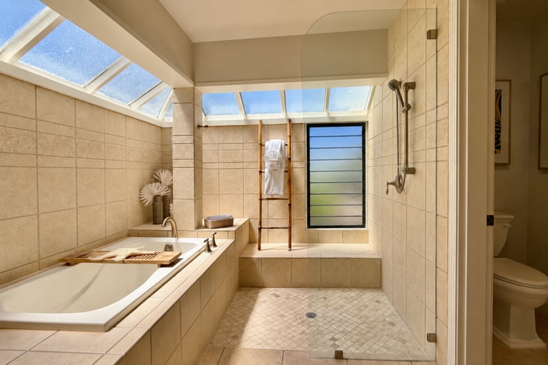 Your primary bathroom's tub and glass-enclosed shower share a bright corner, with a bamboo towel ladder and toilet room tucked to the side.