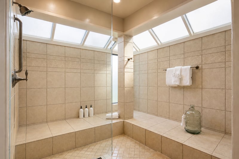 Your primary bathroom's walk-in shower spans two skylighted walls, with a built-in bench and towel bar for easy drying off.