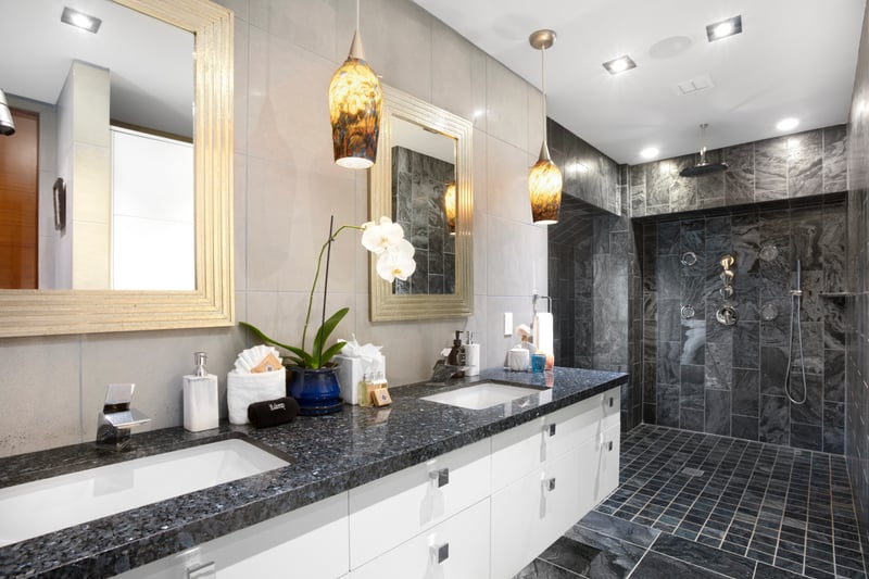 Bold, moody, and spa-ready—this guest bathroom features dramatic tilework, golden lighting, and a luxe walk-in rain shower