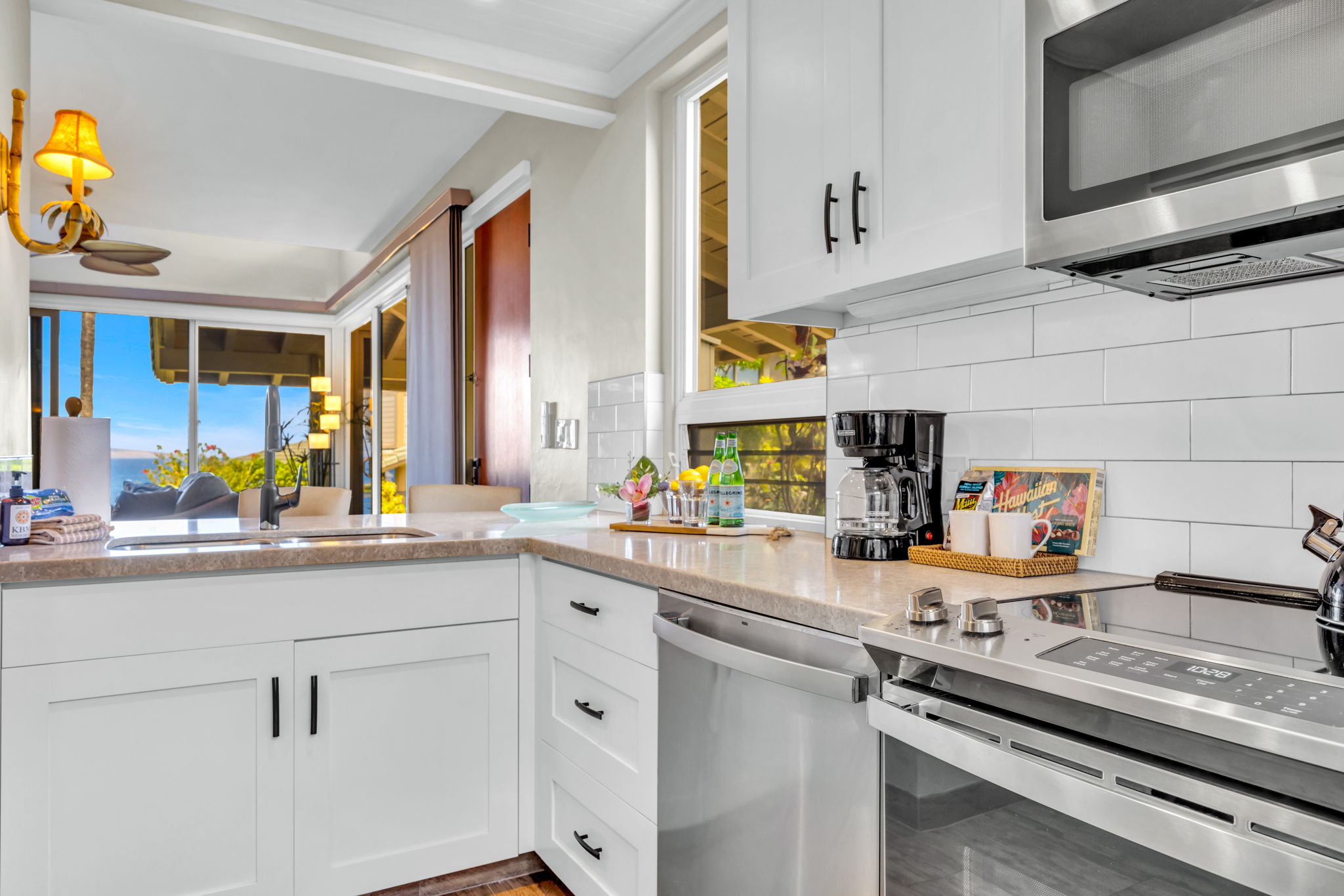 Bright kitchen with modern appliances, bar seating, and surrounded by windows with island views. 