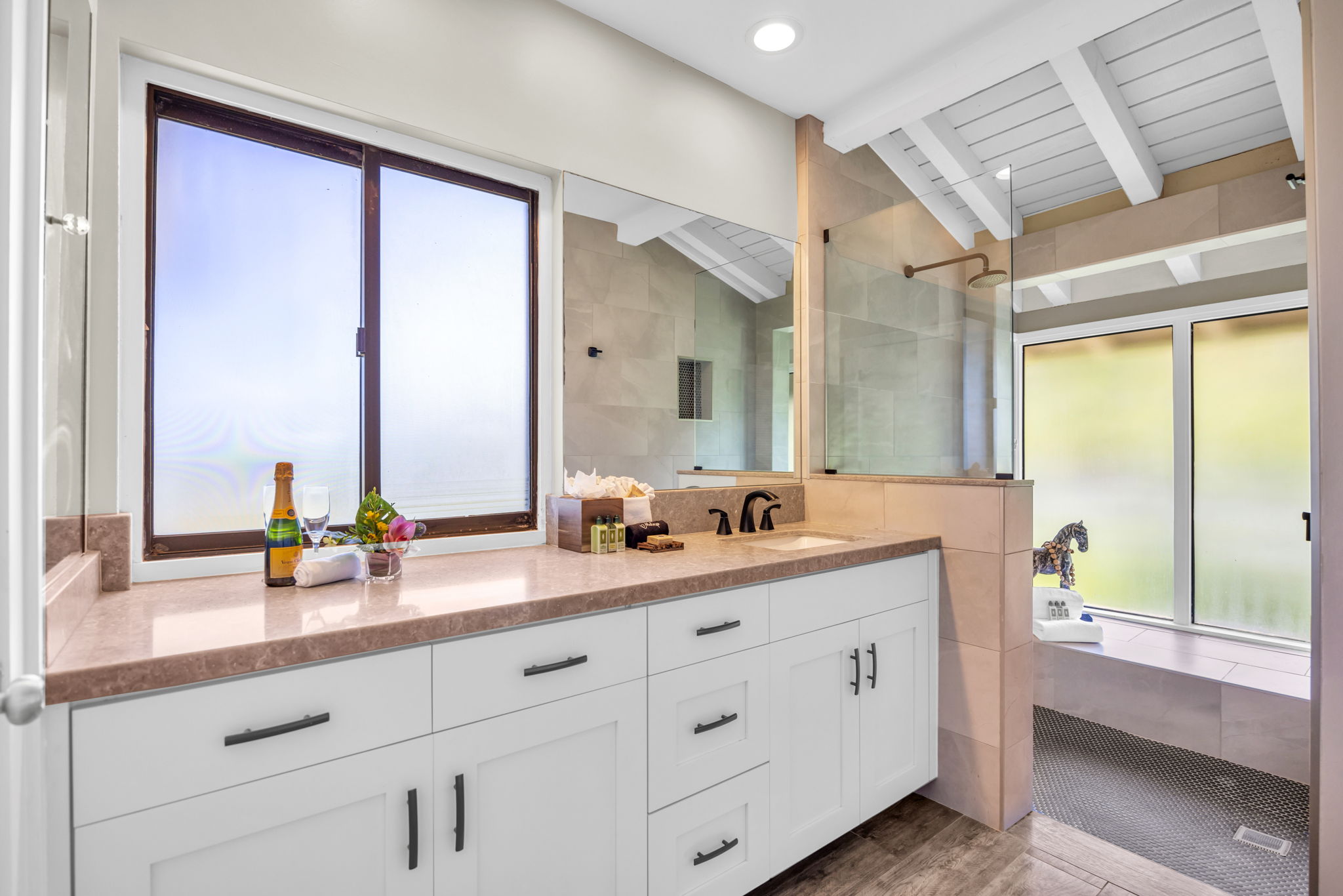 A modern en-suite bathroom with plenty of counter space and a walk-in shower and rainfall shower head. 