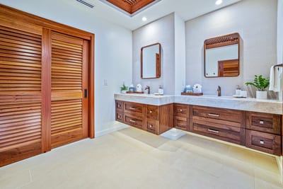 Elegant double vanity bathroom with rich wood accents and lighting.