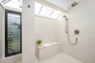 Indulge in modern elegance with dual rainfall showers, a built-in bench, and skylights that bathe the space in sunlight KBV-28G2