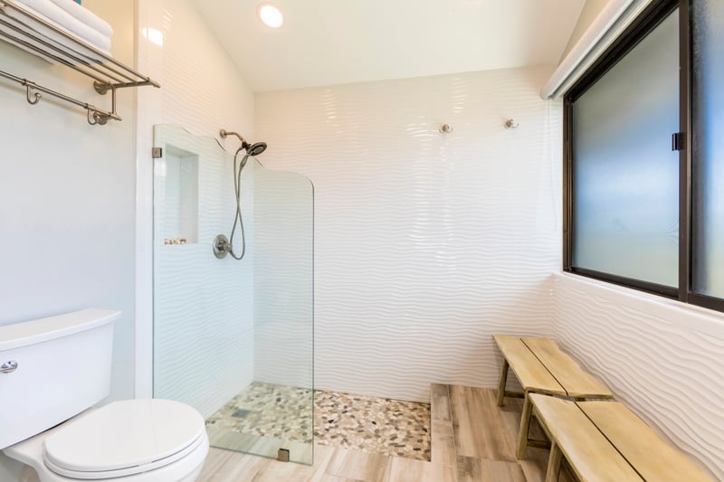 With a stylish bench, open concept, and expansive mirror, this bath is both beautiful and functional