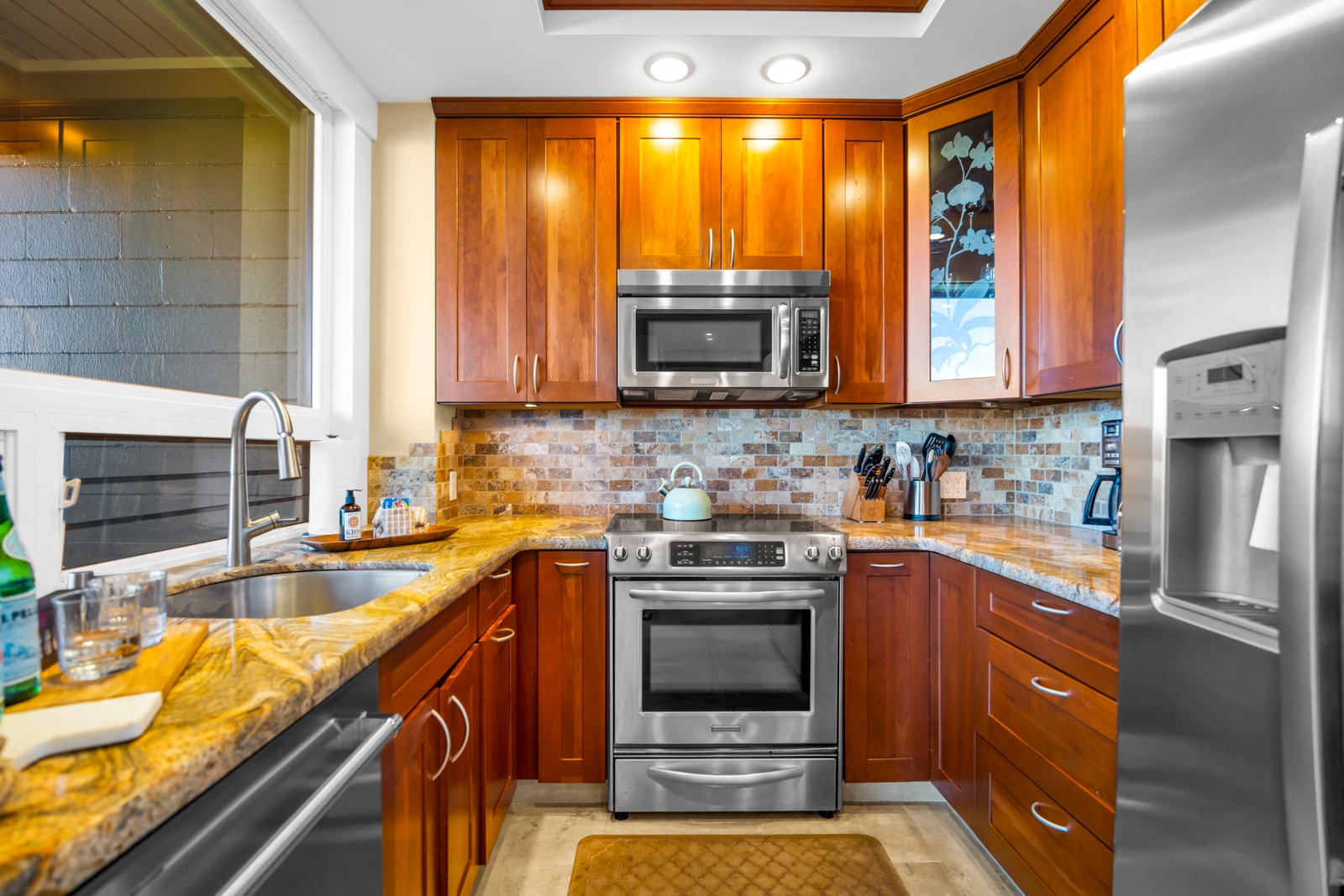Stainless steel appliances, rich cabinetry, and tile backsplash give the kitchen a polished finish.