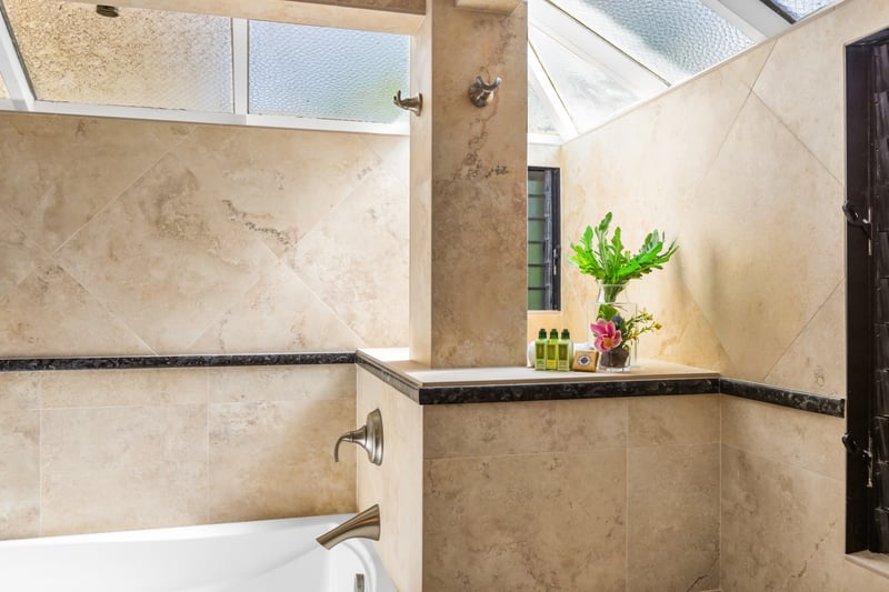 Travertine-style tile and modern fixtures elevate the bathroom’s clean aesthetic.