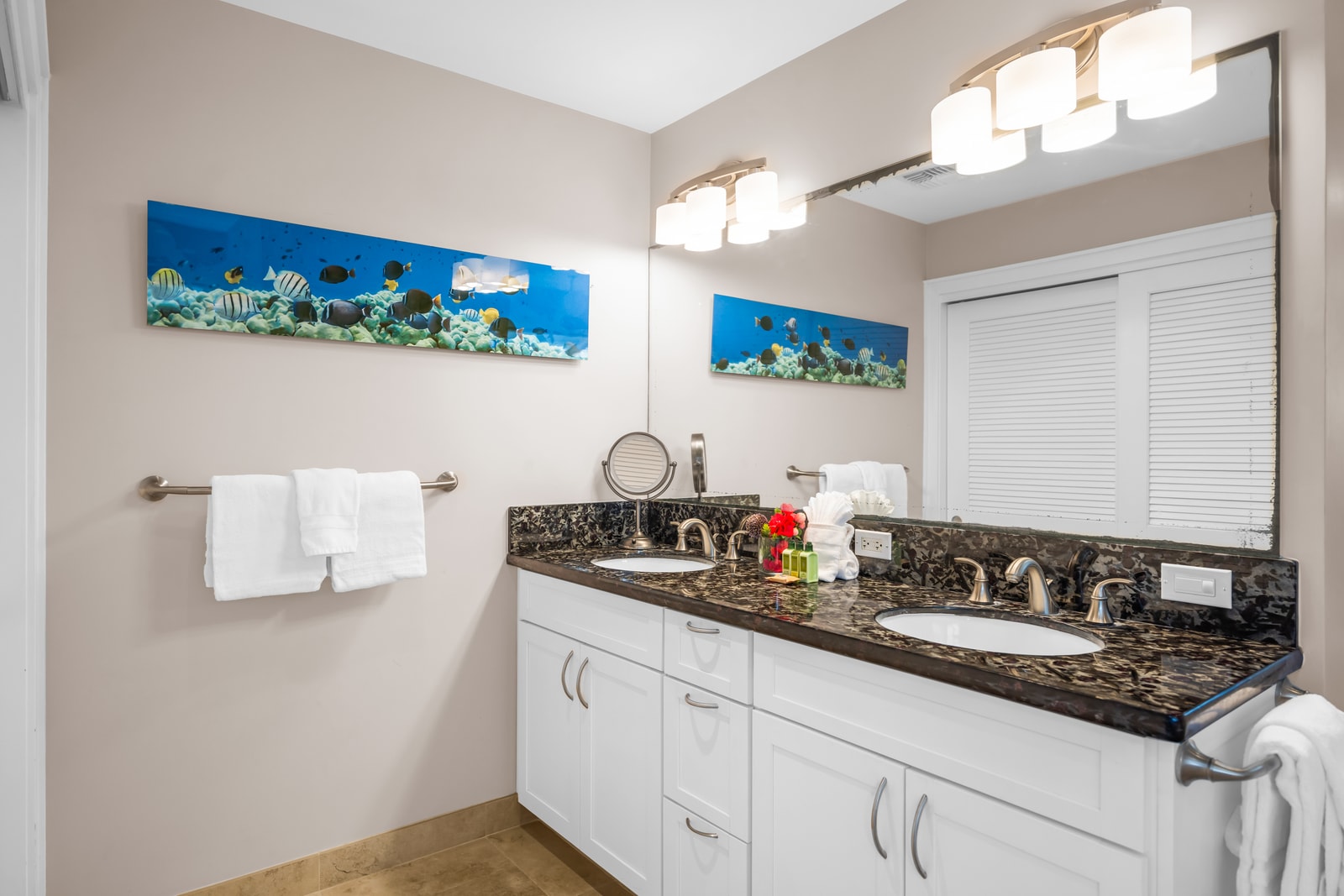 Vanity lighting and dark granite counters make for a bright, polished morning routine.