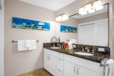 Vanity lighting and dark granite counters make for a bright, polished morning routine.