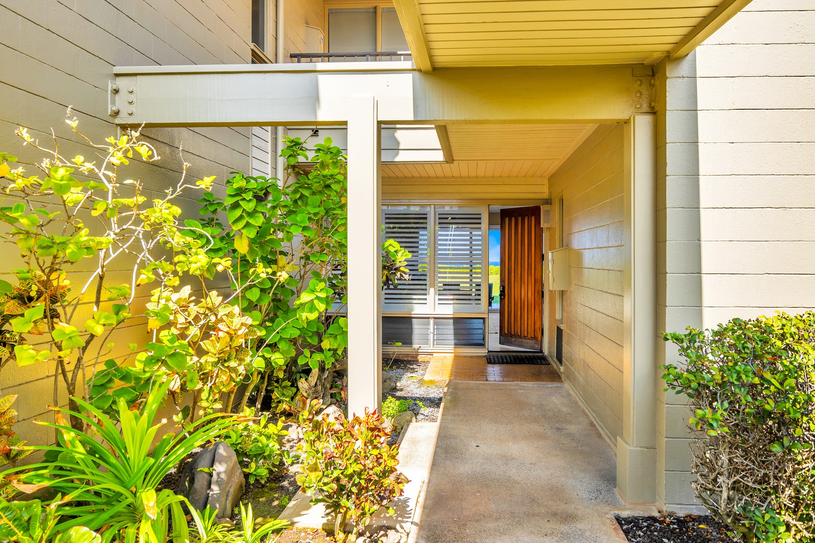 Tropical landscaping surrounds the front path to your ground-floor condo.