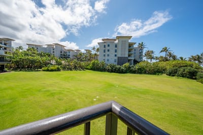 Modern coastal condos overlook lush green lawn under blue skies.