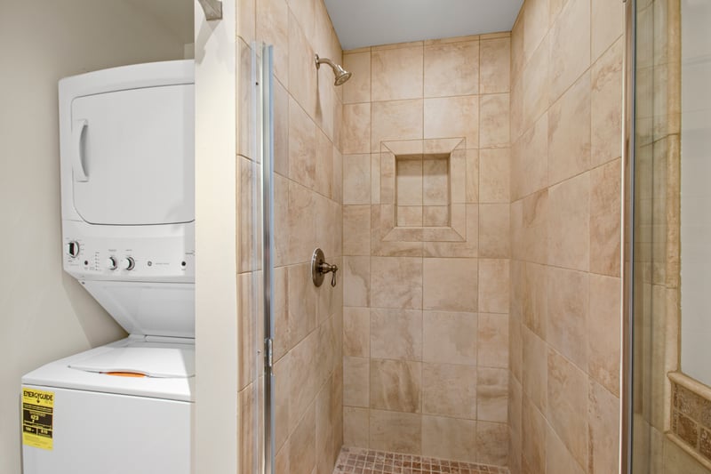 After a day of sun and sand, refresh under a warm stream in the elegant walk-in shower wrapped in travertine tile