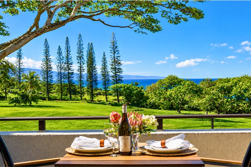 The Kapalua Golf Villas grounds stretch toward the ocean, with lush fairways and the Pacific framed by mature trees.
