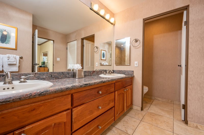 A spacious master bath designed to soothe—boasting dual sinks, ambient lighting, and a walk-in shower wrapped in warm, natural stone