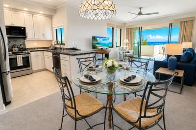 A dedicated dining table for four sits between the kitchen and living room, with ocean views through the lanai's sliding doors.
