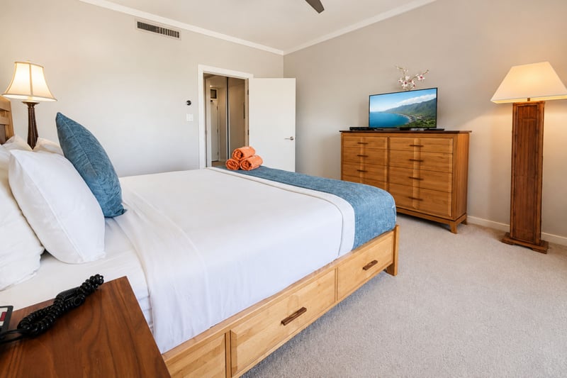 Plenty of storage in the primary bedroom's dresser and nightstands, with a second flat-screen TV for evenings in.