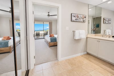A glimpse from the primary bath back into the bedroom and its ocean-view lanai, everything in this suite flows together.