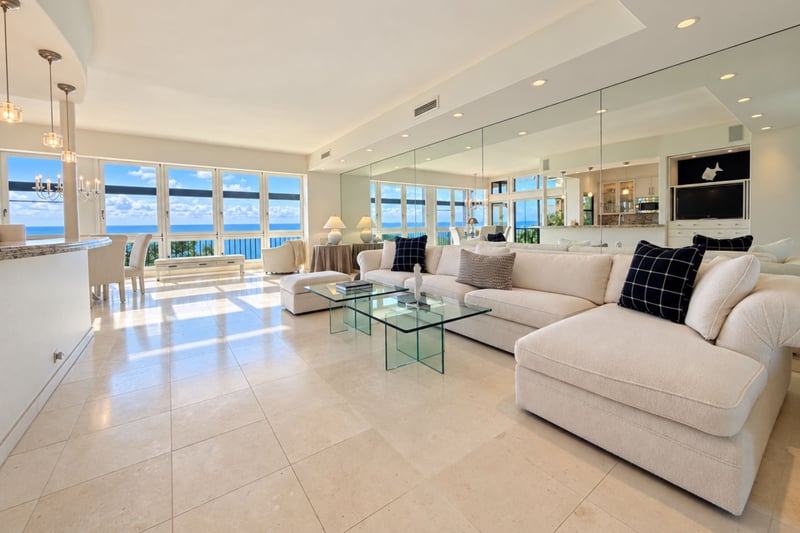 Ocean view living room with a plush sectional sofa and glass coffee tables beneath floor to ceiling windows framing the Pacific.