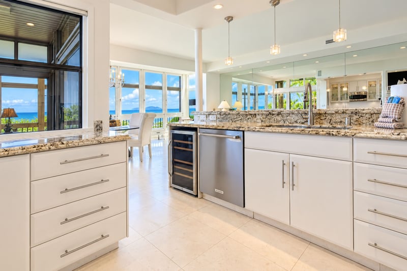 Kitchen prep and bar area with a wine refrigerator, dishwasher, and granite counters set against an ocean view backdrop.