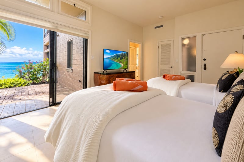 Second bedroom offering a bright retreat with direct patio access and a burl wood media console.