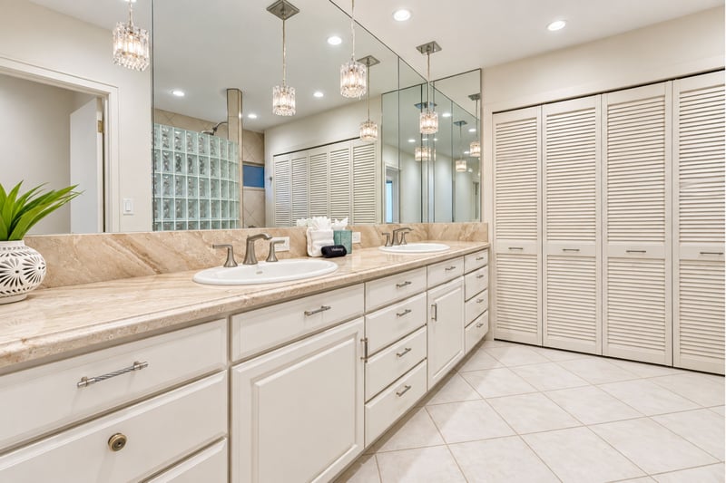 Primary ensuite bath with dual vanities, crystal pendant lighting, and abundant louvered storage.