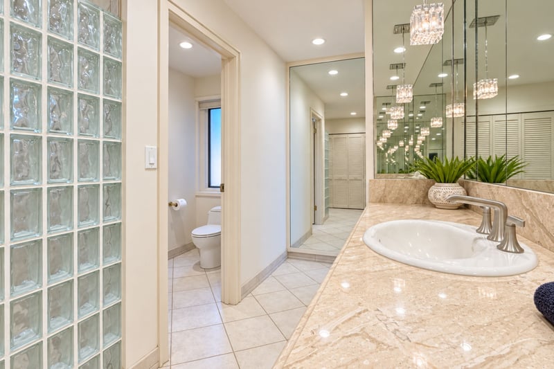 Primary ensuite bath with a glass block walk in shower and private water closet just steps from the dual sink vanity.