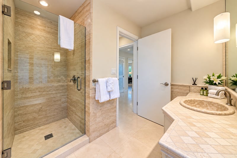 Guest bath walk in shower with a sleek tile surround and easy access to the adjoining water closet.