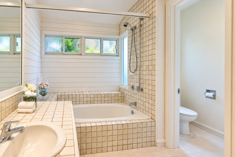 Second guest bath with a deep soaking tub, tile surround, and a private water closet.