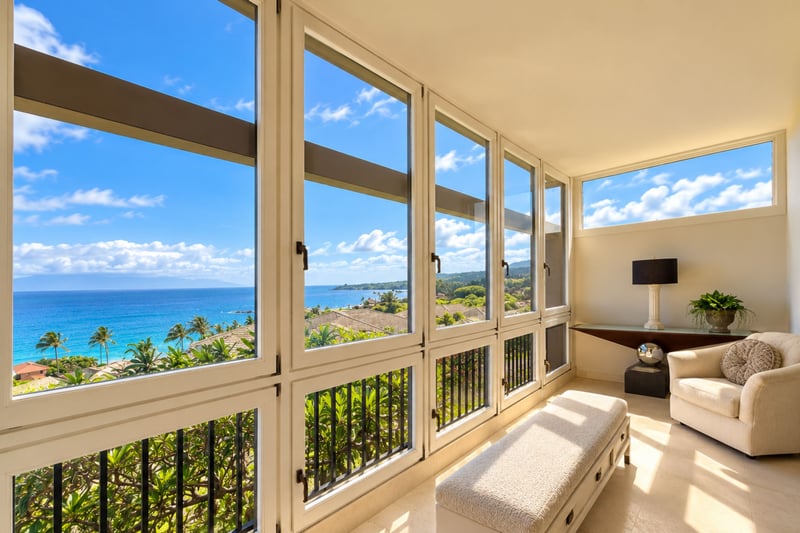 Bright reading corner with an upholstered armchair and window bench overlooking the coastline.